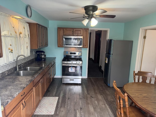 kitchen with dark wood-style floors, ceiling fan, decorative backsplash, a sink, and appliances with stainless steel finishes