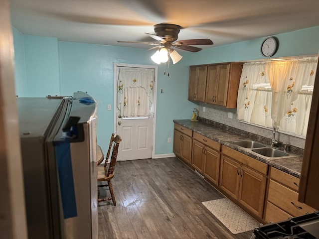 kitchen with dark countertops, ceiling fan, dark wood finished floors, brown cabinetry, and a sink