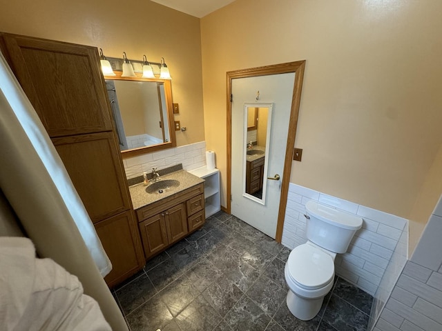 bathroom featuring a wainscoted wall, toilet, tile walls, and vanity