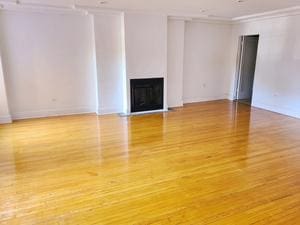 unfurnished living room with a fireplace, wood finished floors, and crown molding