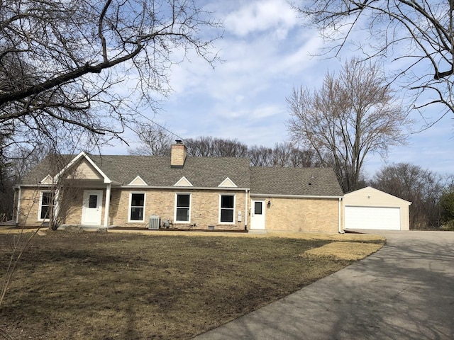 view of front facade featuring an outbuilding, a front yard, driveway, a shingled roof, and a chimney