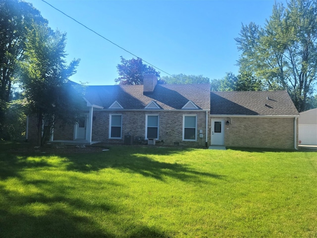 rear view of house with brick siding, a lawn, and a chimney