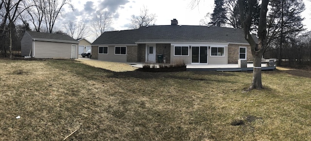 rear view of property with brick siding, a lawn, a chimney, an outdoor structure, and a patio