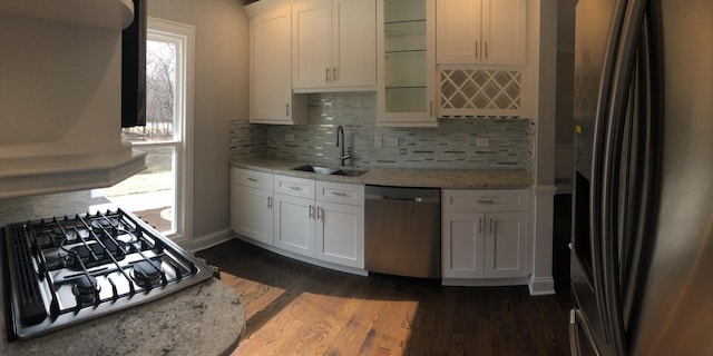 kitchen featuring a sink, appliances with stainless steel finishes, white cabinets, glass insert cabinets, and light stone countertops