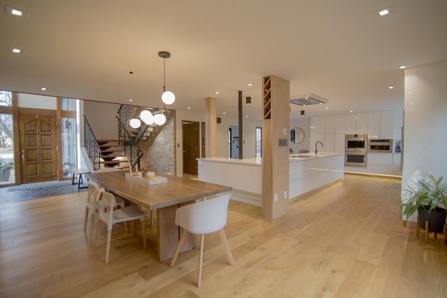 dining room with stairway, recessed lighting, light wood finished floors, and expansive windows