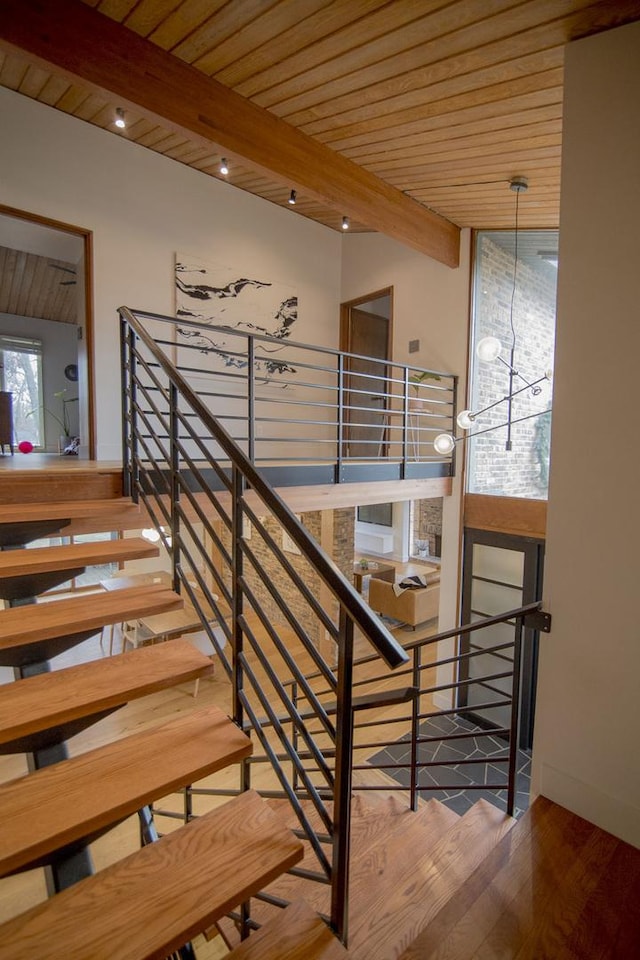 staircase with baseboards, beam ceiling, wood finished floors, and wooden ceiling