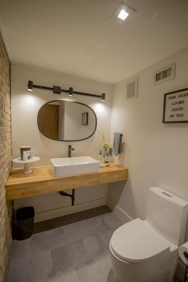 bathroom featuring visible vents, toilet, baseboards, and a sink