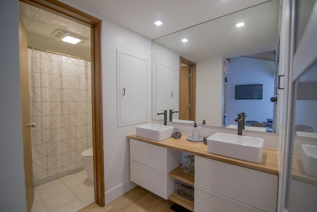 bathroom featuring double vanity, recessed lighting, toilet, and a sink