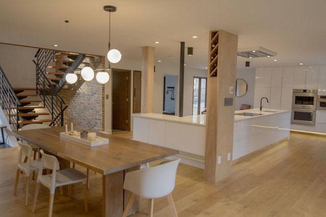 dining room with recessed lighting, light wood-style floors, and stairs