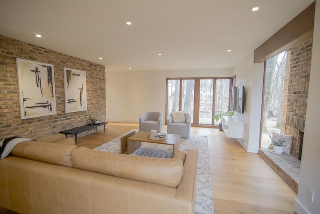 living area featuring recessed lighting, light wood-style floors, baseboards, and brick wall