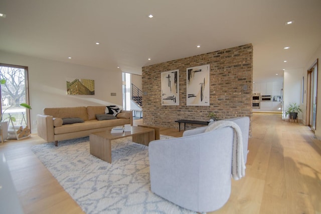 living area with recessed lighting, light wood-style floors, a healthy amount of sunlight, and brick wall