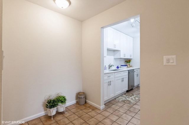 interior space with light tile patterned floors, baseboards, a sink, light countertops, and white cabinetry