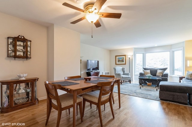 dining room with light wood finished floors, visible vents, baseboards, and ceiling fan