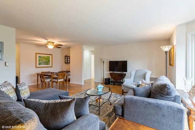 living room featuring wood finished floors, baseboards, and ceiling fan