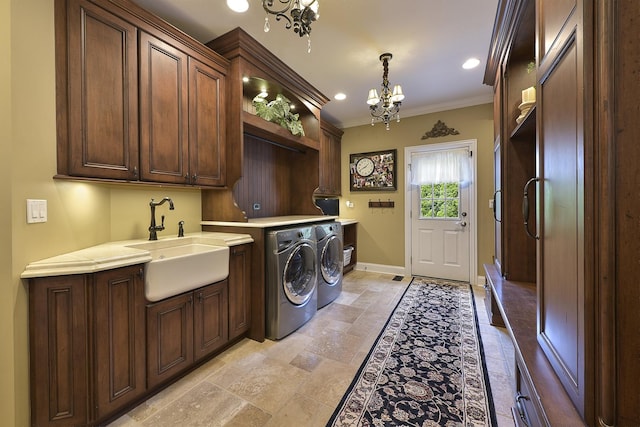 washroom with baseboards, an inviting chandelier, cabinet space, a sink, and independent washer and dryer