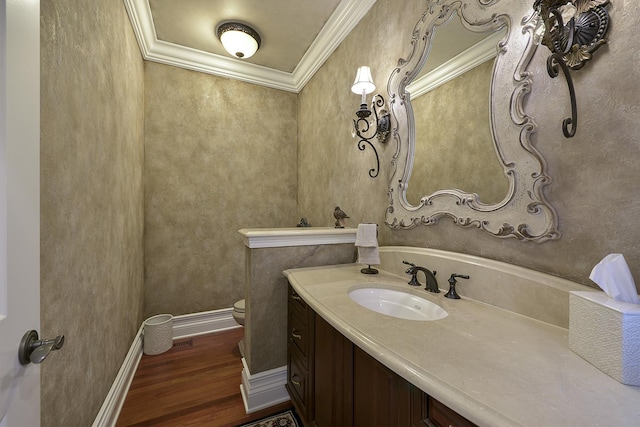 bathroom with toilet, wood finished floors, crown molding, baseboards, and vanity