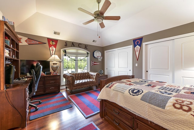 bedroom with visible vents, two closets, a ceiling fan, dark wood-style floors, and lofted ceiling