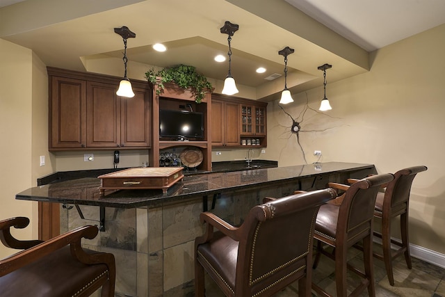 bar with decorative light fixtures, a raised ceiling, and baseboards