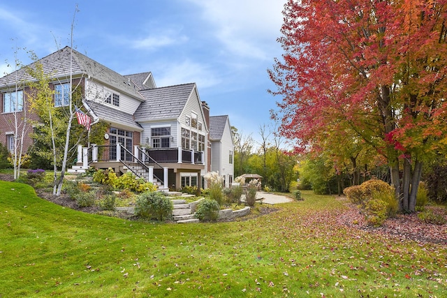 back of property with stairway, a wooden deck, a lawn, a sunroom, and a patio area