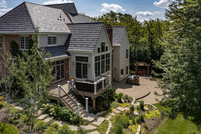 back of property with stairs, a wooden deck, a patio area, and a chimney