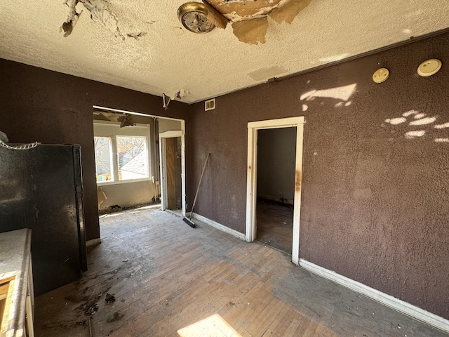 interior space featuring visible vents, a textured ceiling, baseboards, and hardwood / wood-style floors