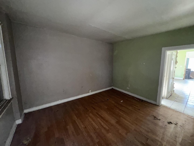 spare room with baseboards and wood finished floors