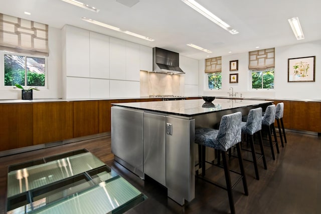 kitchen with a wealth of natural light, modern cabinets, a sink, and wall chimney range hood