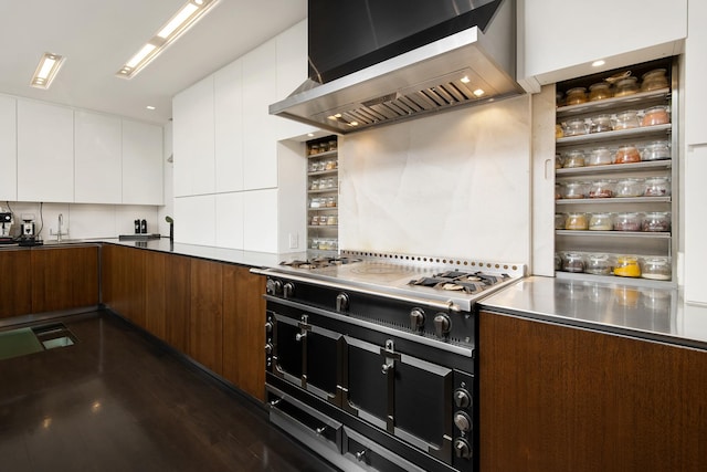 kitchen with modern cabinets, stainless steel countertops, stovetop, white cabinets, and wall chimney range hood