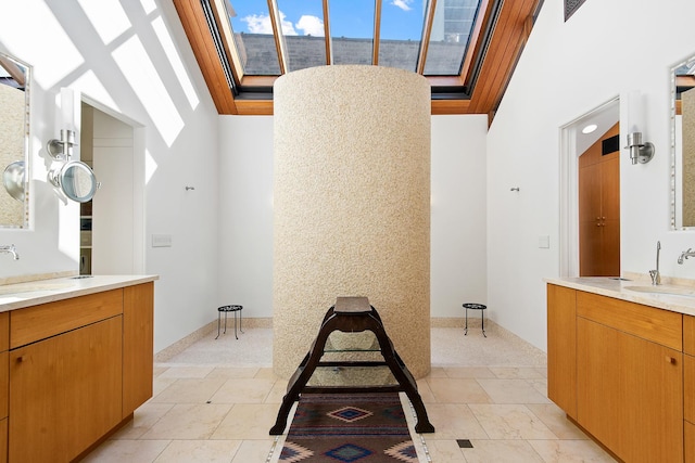 full bath with a sink, two vanities, and a skylight