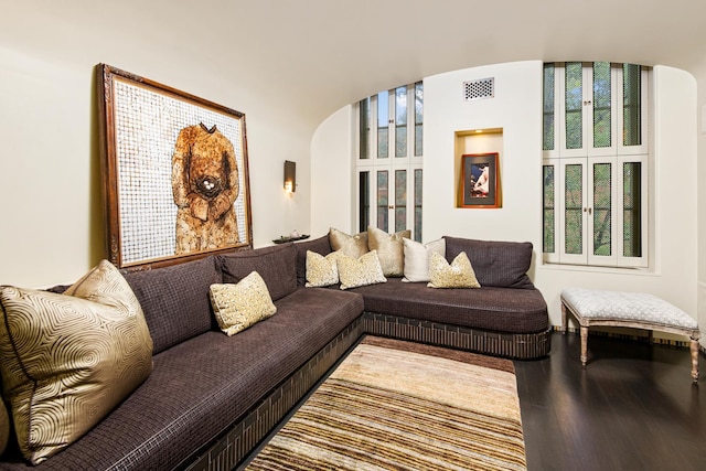 living area with visible vents, arched walkways, and wood finished floors