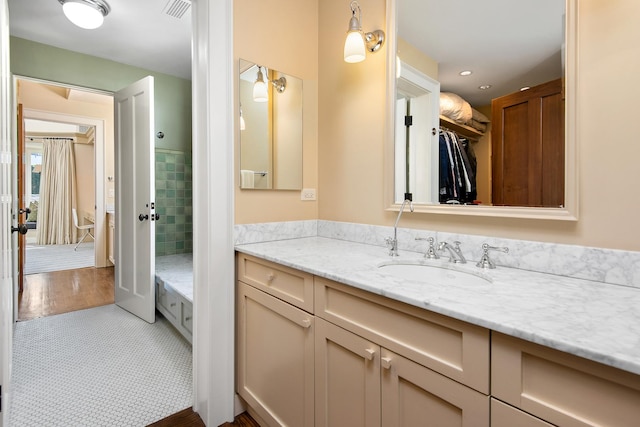 bathroom with visible vents, a walk in closet, and vanity