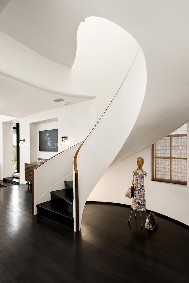 staircase with visible vents, baseboards, and wood finished floors