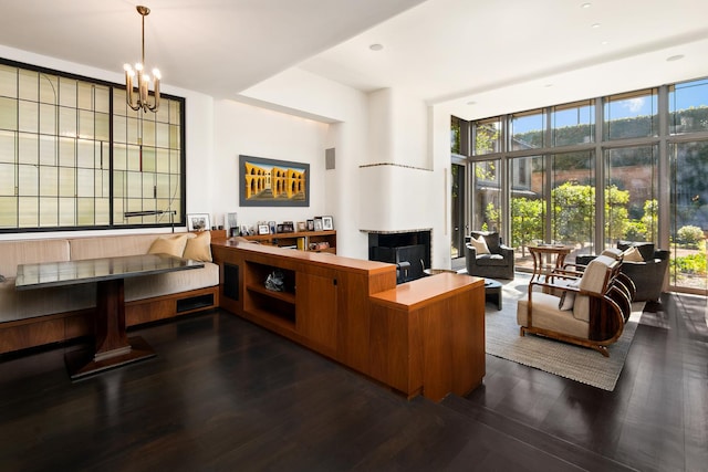 living room with dark wood finished floors, a chandelier, a wall of windows, and a wealth of natural light