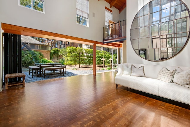 living area featuring wood ceiling, beamed ceiling, wood finished floors, and a towering ceiling