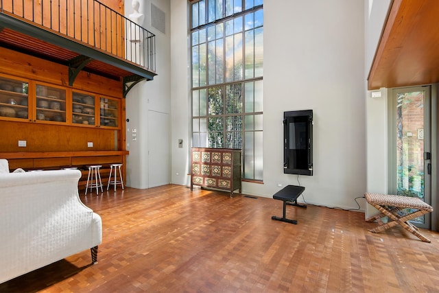 living area featuring a high ceiling, wood finished floors, visible vents, and expansive windows