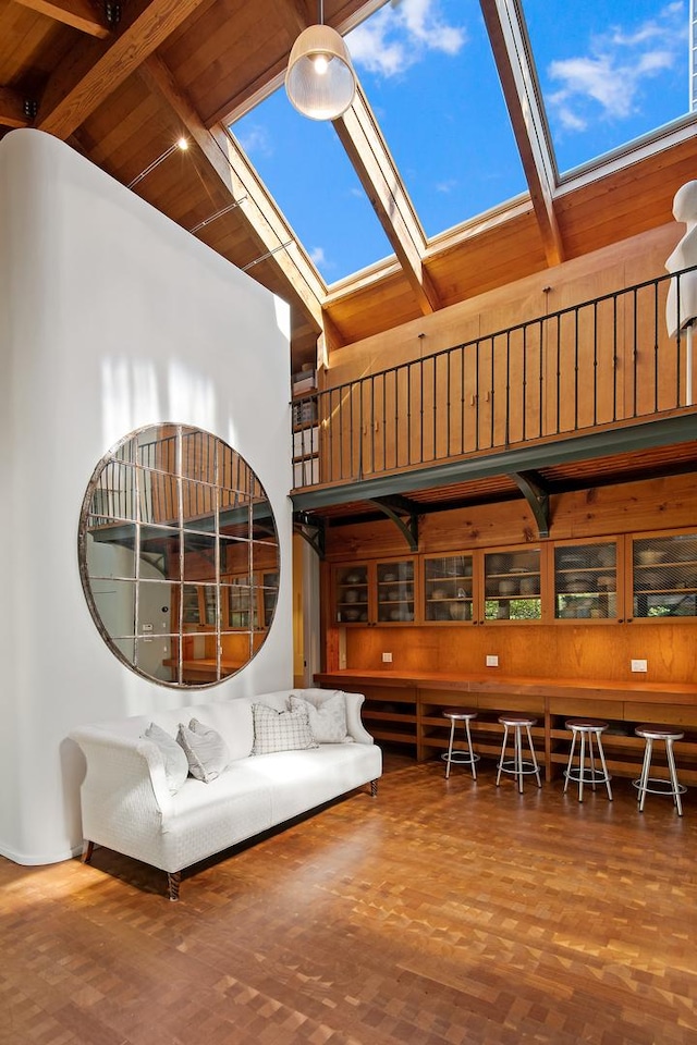 interior space with beam ceiling, high vaulted ceiling, a skylight, and parquet flooring