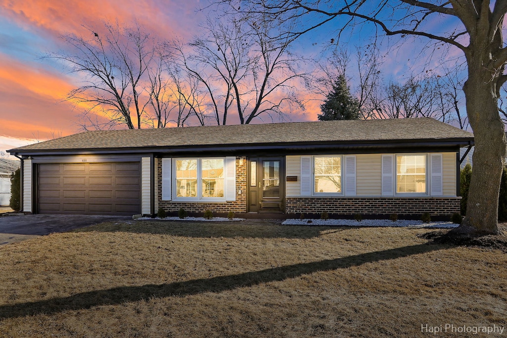 view of front facade with driveway, a lawn, an attached garage, and entry steps