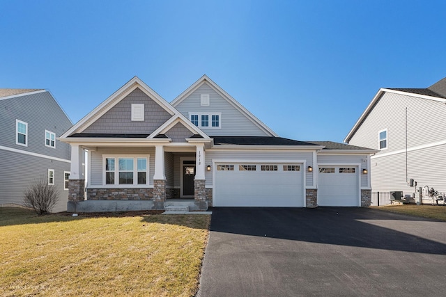 view of front of house featuring a front lawn, an attached garage, stone siding, and driveway