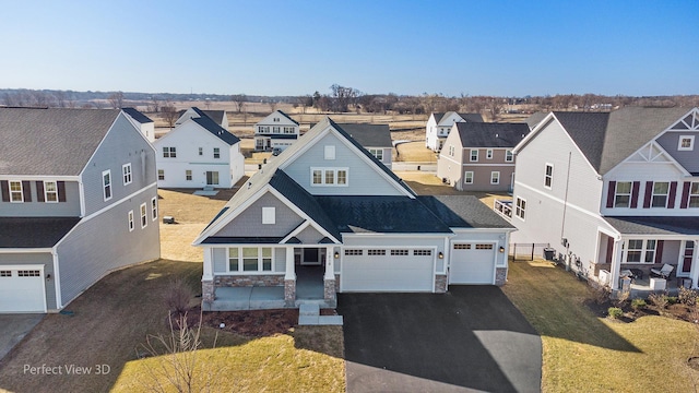 view of front of property featuring a front yard, driveway, a garage, stone siding, and a residential view