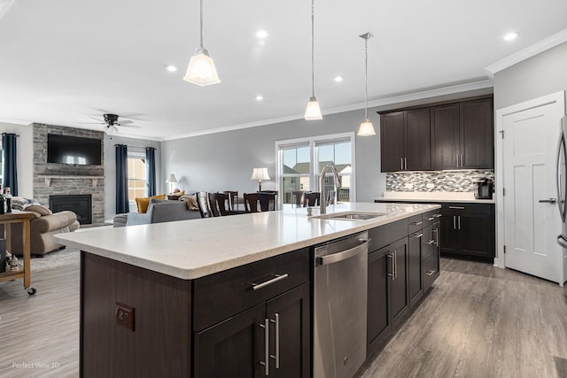 kitchen featuring backsplash, stainless steel dishwasher, wood finished floors, a ceiling fan, and a sink