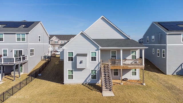 rear view of property with stairway, fence, a shingled roof, a lawn, and a residential view