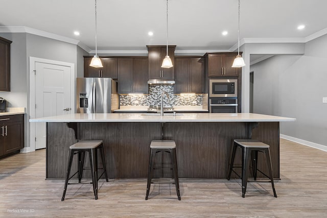 kitchen featuring dark brown cabinetry, decorative backsplash, stainless steel appliances, and a sink