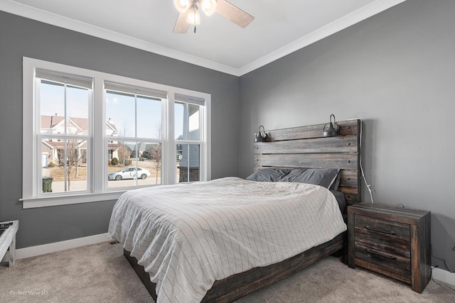 carpeted bedroom with ceiling fan, baseboards, and ornamental molding