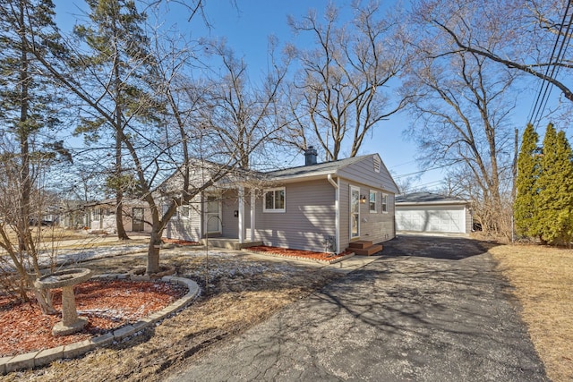 view of front of property featuring a detached garage, an outbuilding, and a chimney