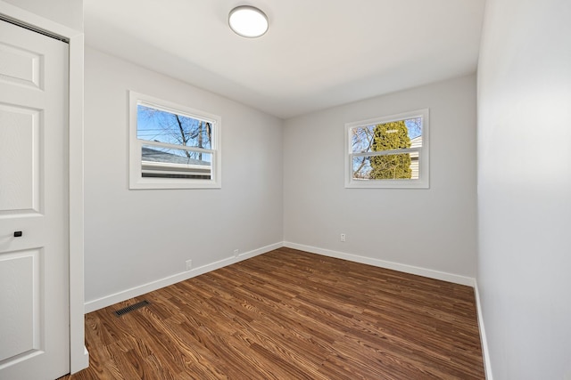 spare room with visible vents, baseboards, and dark wood-style flooring