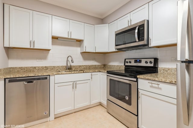 kitchen with light stone counters, a sink, decorative backsplash, white cabinets, and appliances with stainless steel finishes