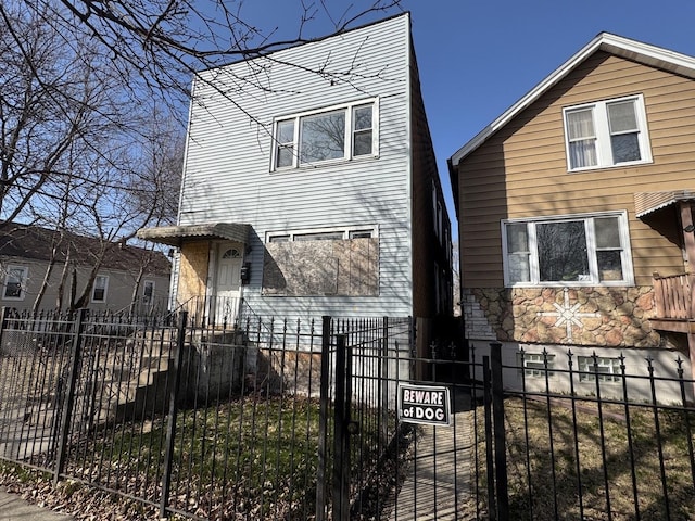 view of front of home featuring a fenced front yard, stone siding, and a gate