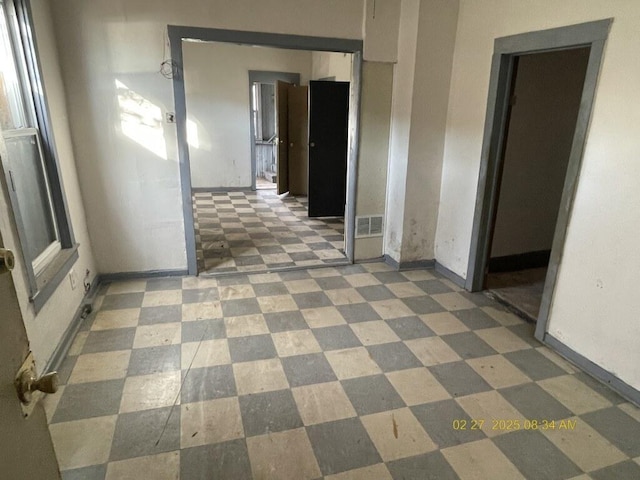 hallway featuring tile patterned floors, visible vents, and baseboards