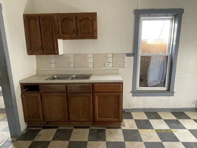 kitchen with tile patterned floors, decorative backsplash, light countertops, and a sink