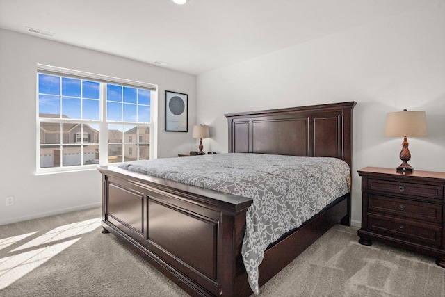 bedroom featuring visible vents, light carpet, and baseboards